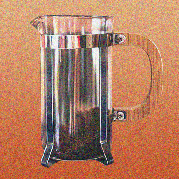 A glass french press brewer with dry coarse ground coffee at the bottom of it, on a yellow and orange gradient background.